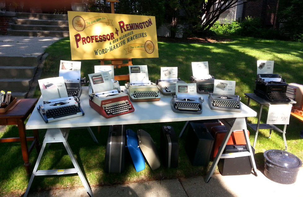 Typewriters set up on outdoor rummage sale table.