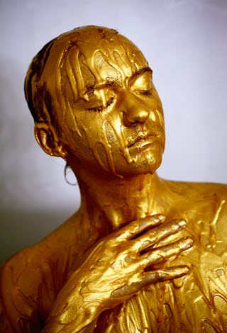 Person of indeterminate gender covered with thick gold paint