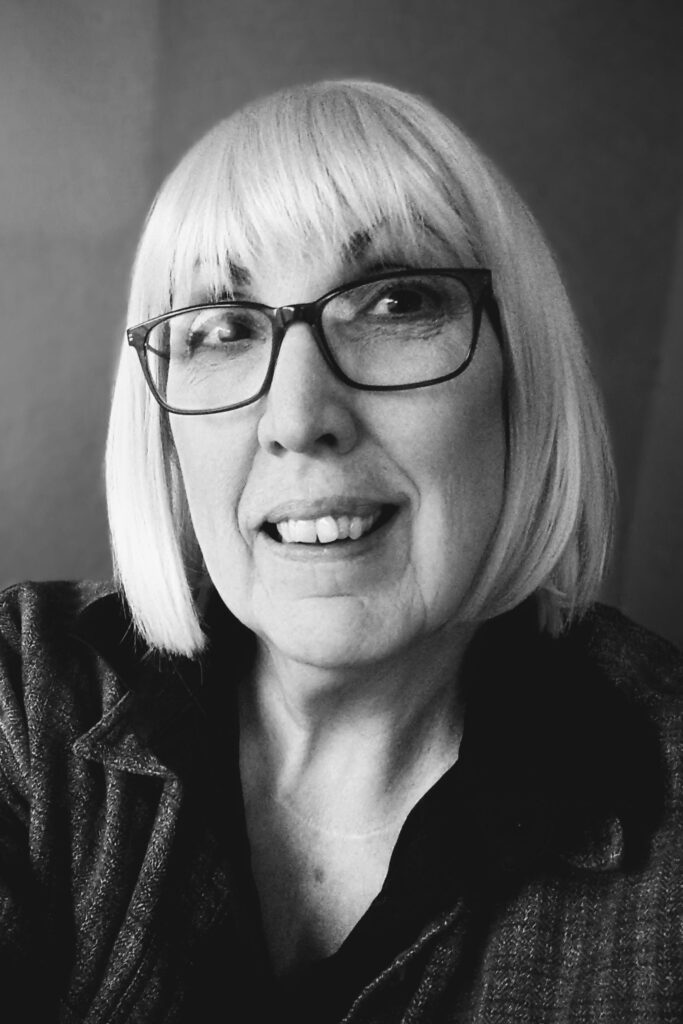 Black and white portrait of caucasion, female-presenting person with shoulder length bob and glasses.