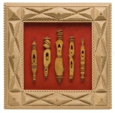 Tramp art chipped frame displays a small collection of elaborately carved whimsy sticks.